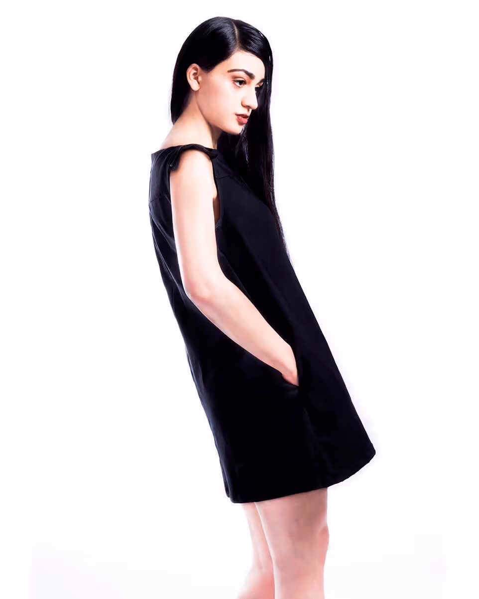 Modelo mirando de lado, con fondo blanco y usando vestido azul marino