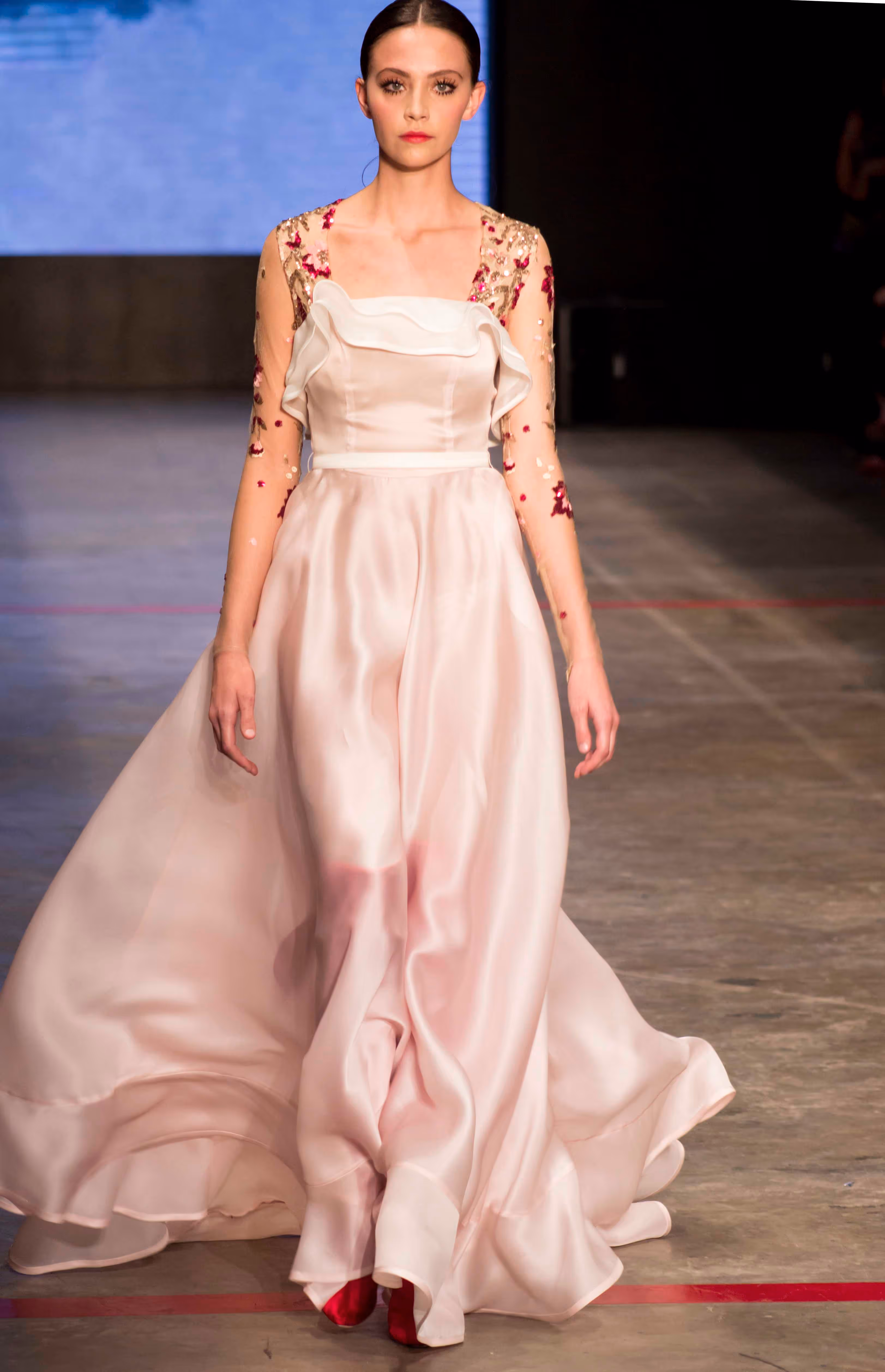 Modelo en pasarela viendo a la camara con vestido rosado