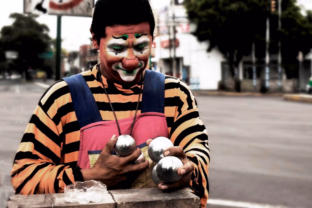 Payaso en calle mexicana sosteniendo pelotas de malabares.
