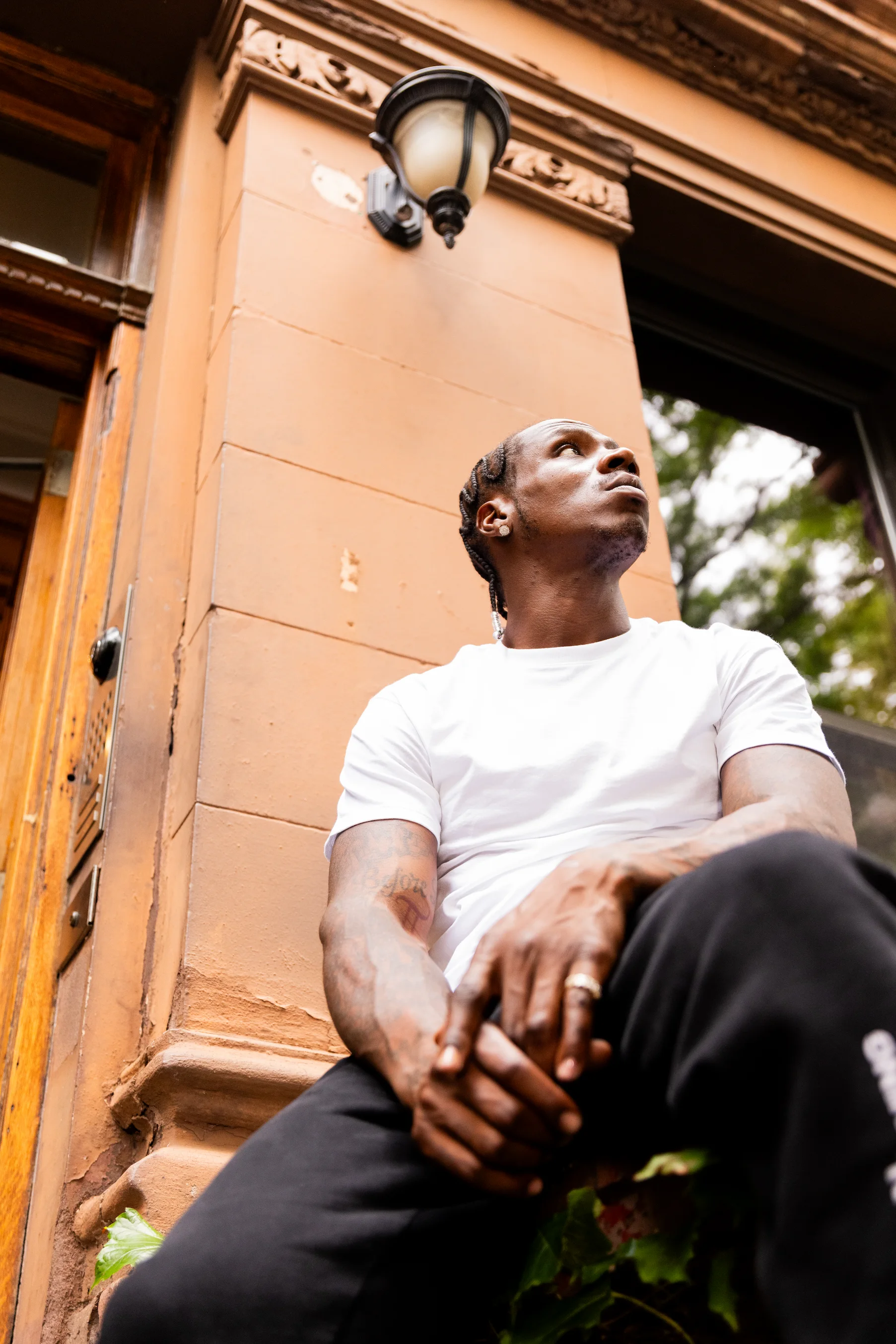 Model sitting on a Harlem stoop wearing Hanes white tee for “50 Years of Hip-Hop” campaign — So & So Productions fashion photo.