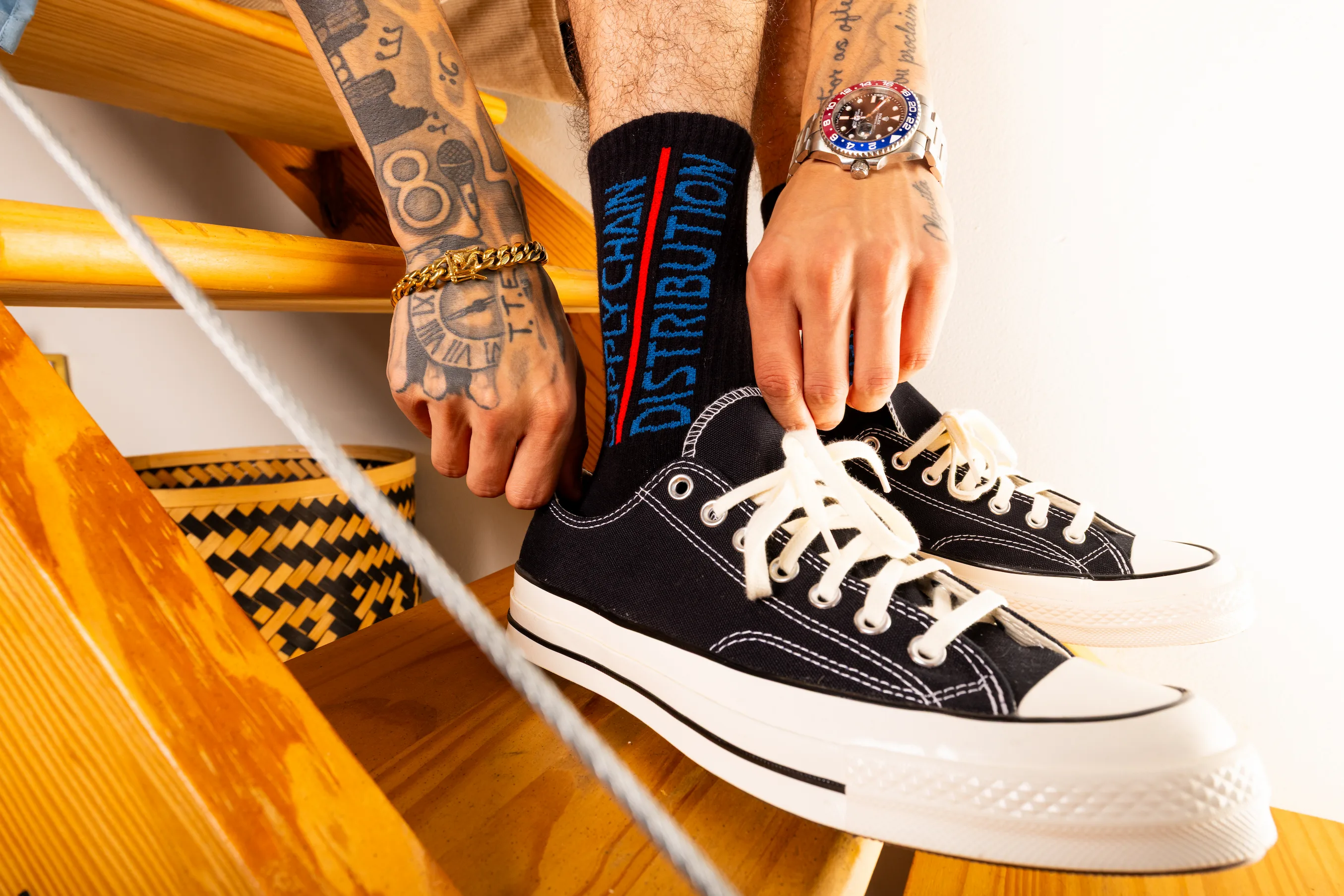 Detail shot of Supply Chain Distro logo on sock captured in apartment setting — So & So Productions fashion photo.