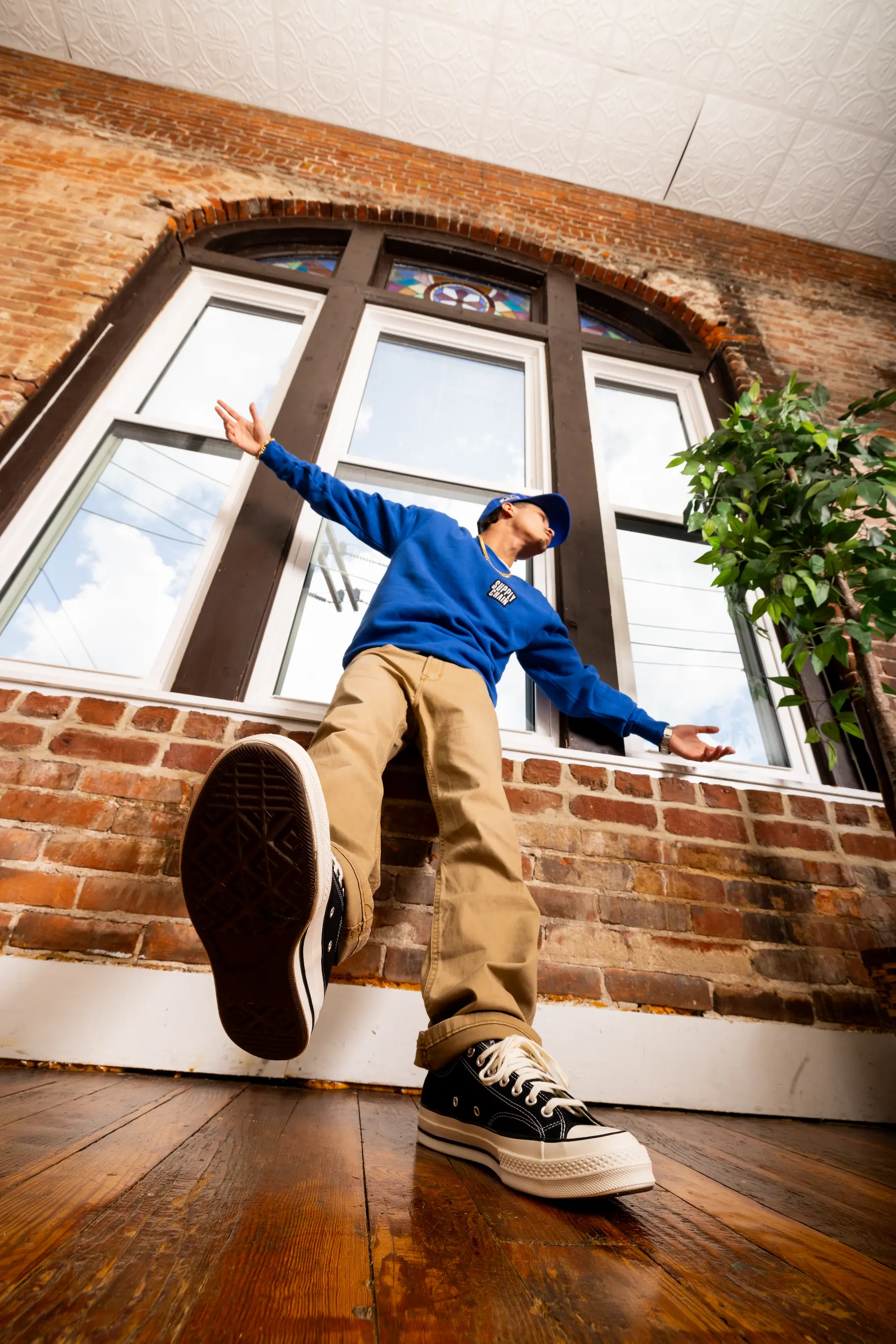 Model posing in front of apartment window wearing Supply Chain Distro belt — So & So Productions lifestyle fashion photography.