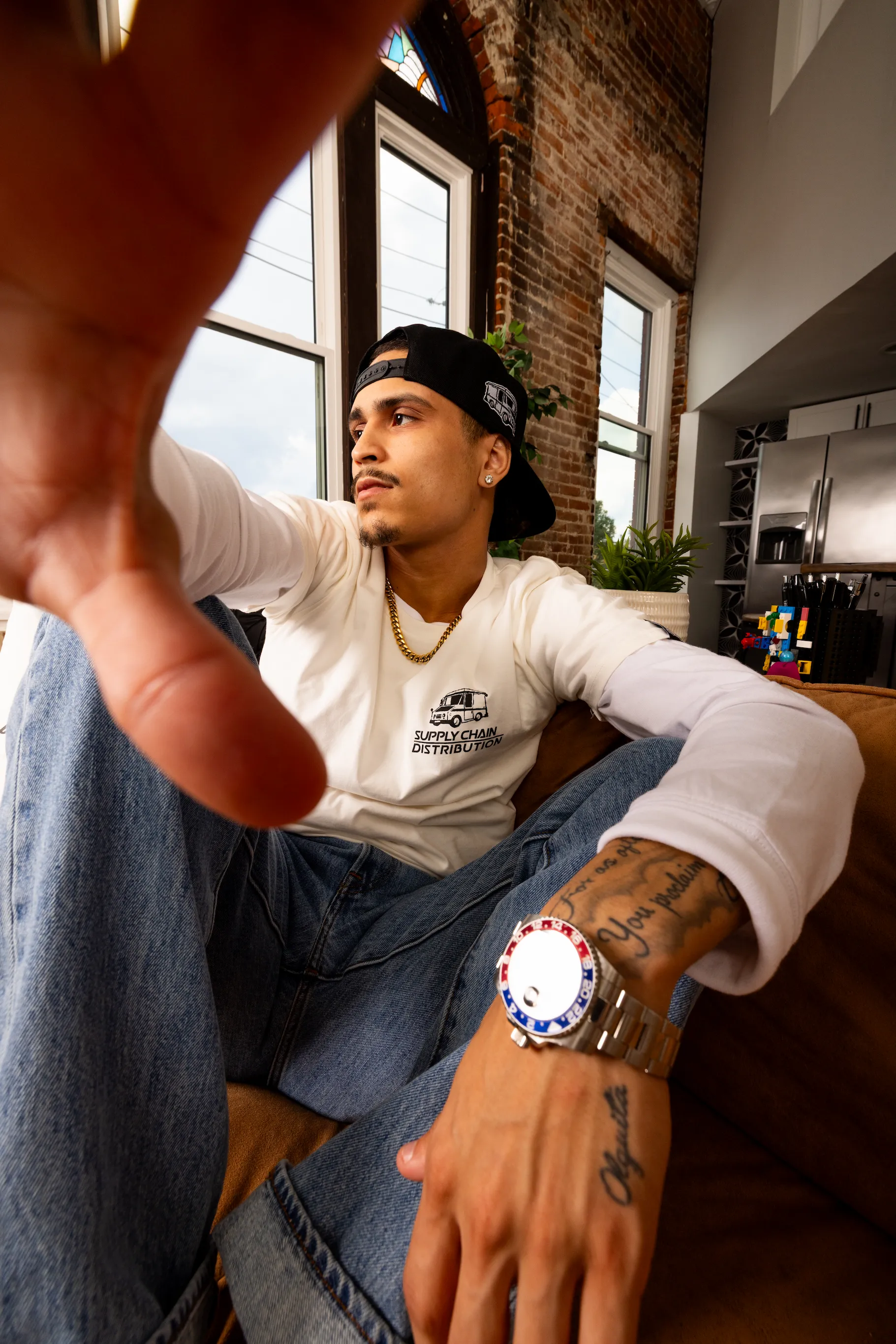 Portrait of model wearing Supply Chain Distro tee in cozy apartment corner — So & So Productions creative image.