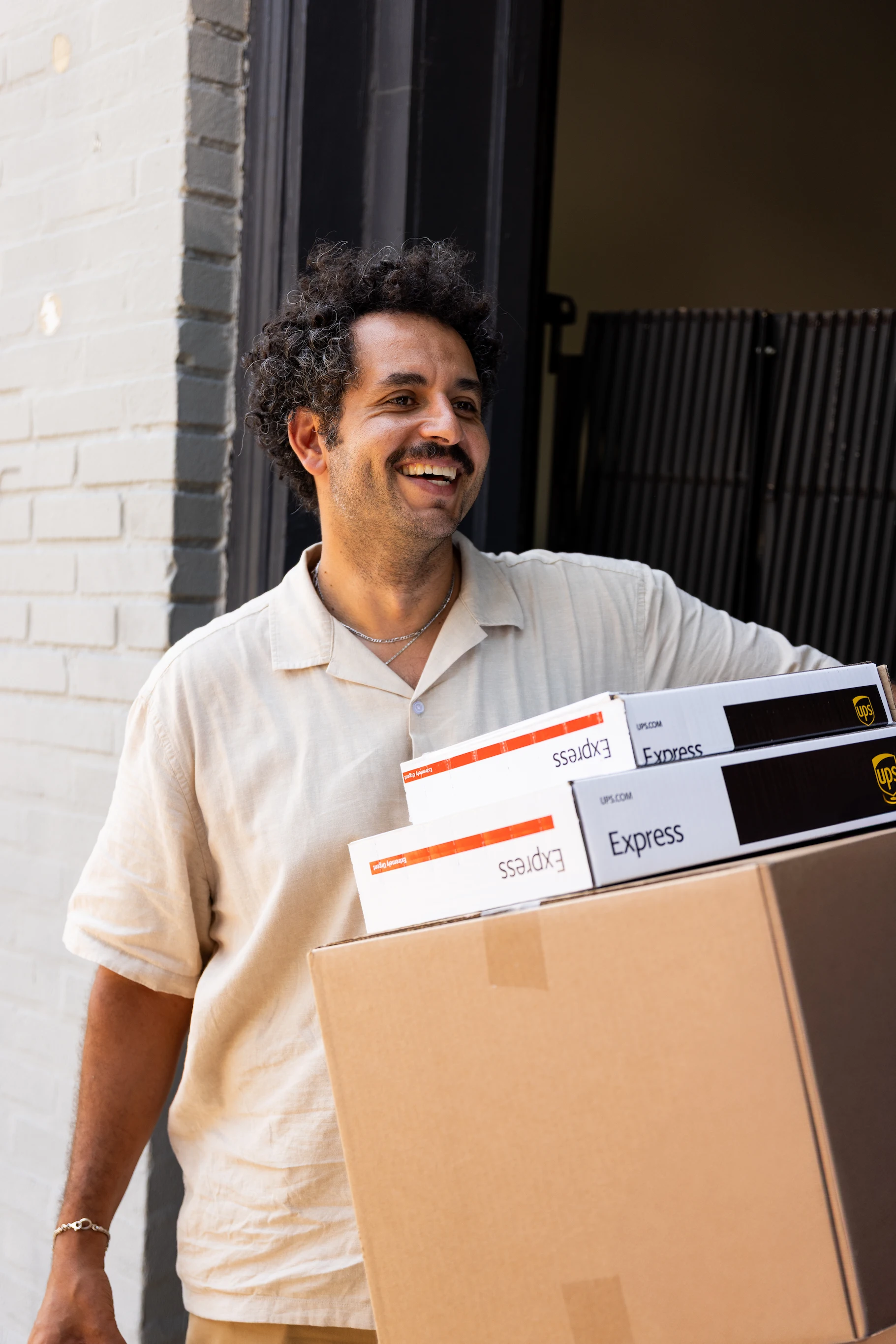 Kareem Rahma holding stacked boxes during UPS × Kareem Rahma Business Trips shoot — So & So Productions brand photography.