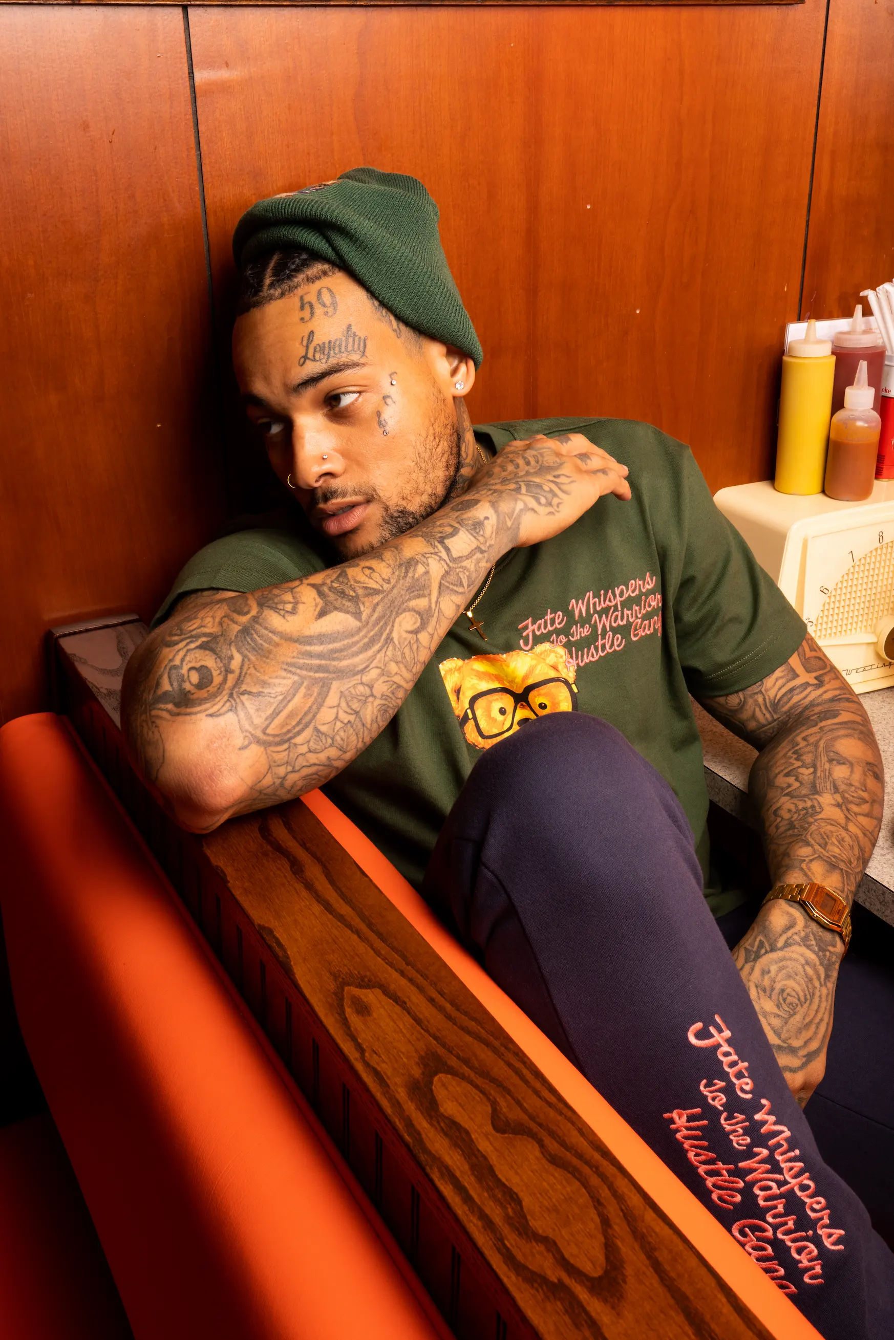 Model sitting in vintage booth at Doumar’s wearing AKOO shirt — So & So Productions urban culture photography.