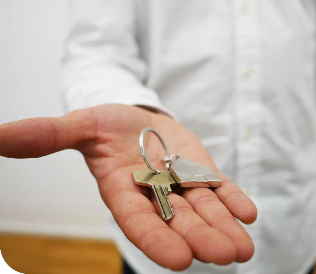 Hand holding a key on a keyring with a house-shaped keychain.