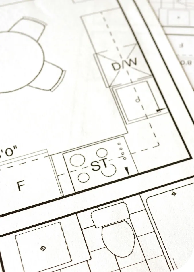Close-up of a printed architectural floor plan showing a kitchen area with a stove, dishwasher, dining table, and a bathroom with a toilet.