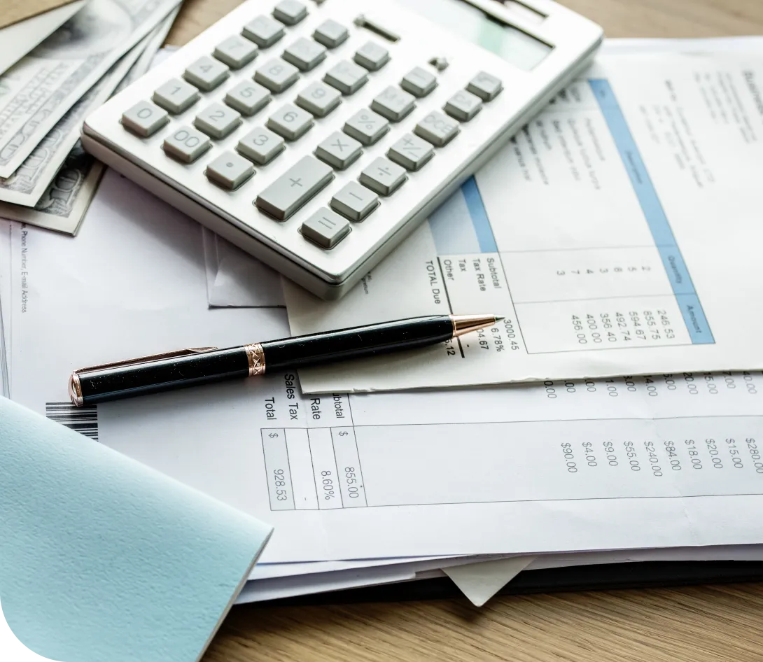Close-up of a calculator, black pen, US dollar bills, and financial documents on a wooden table.