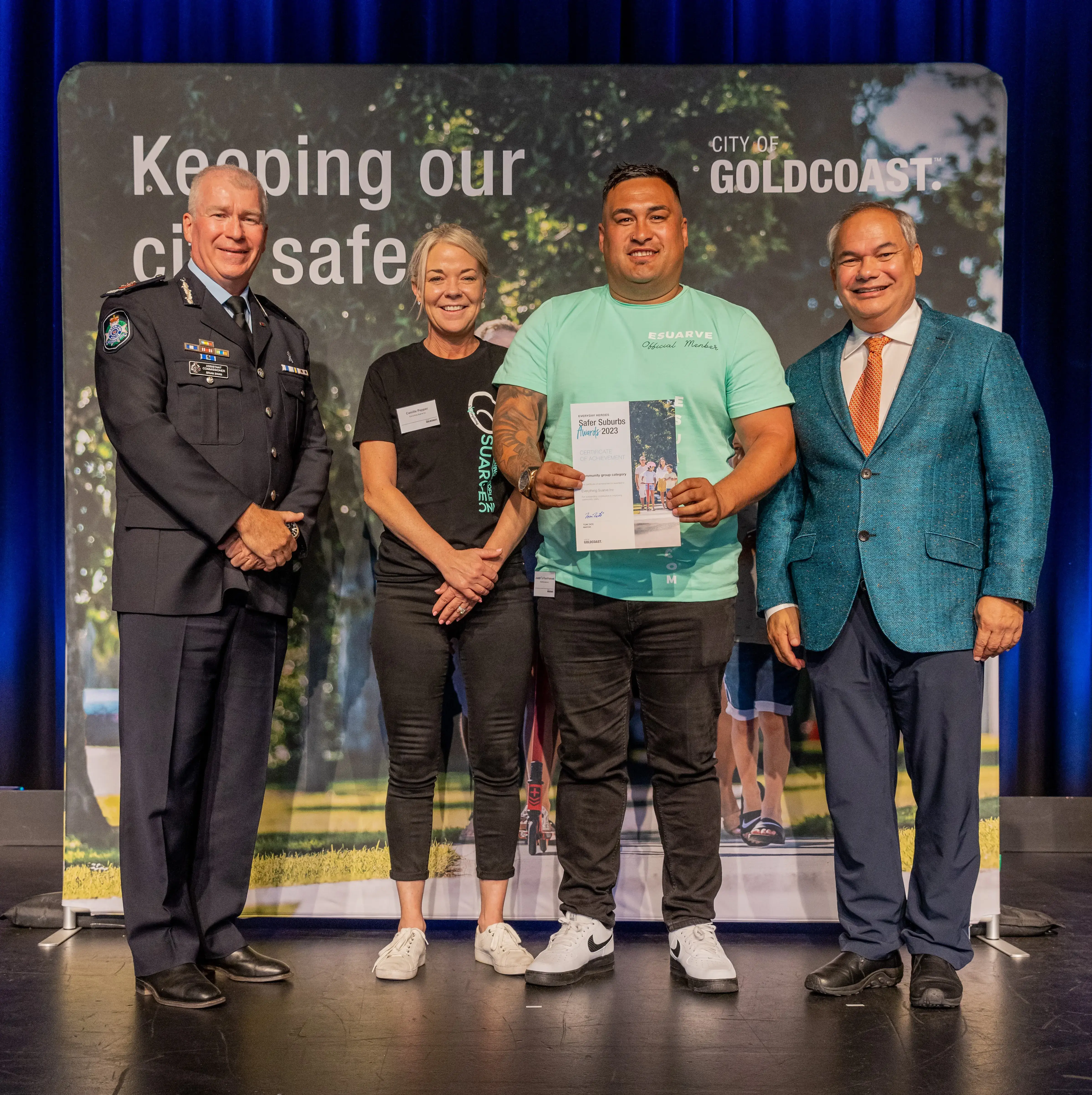Four people standing in front of a City of Gold Coast safety banner, one holding a certificate.