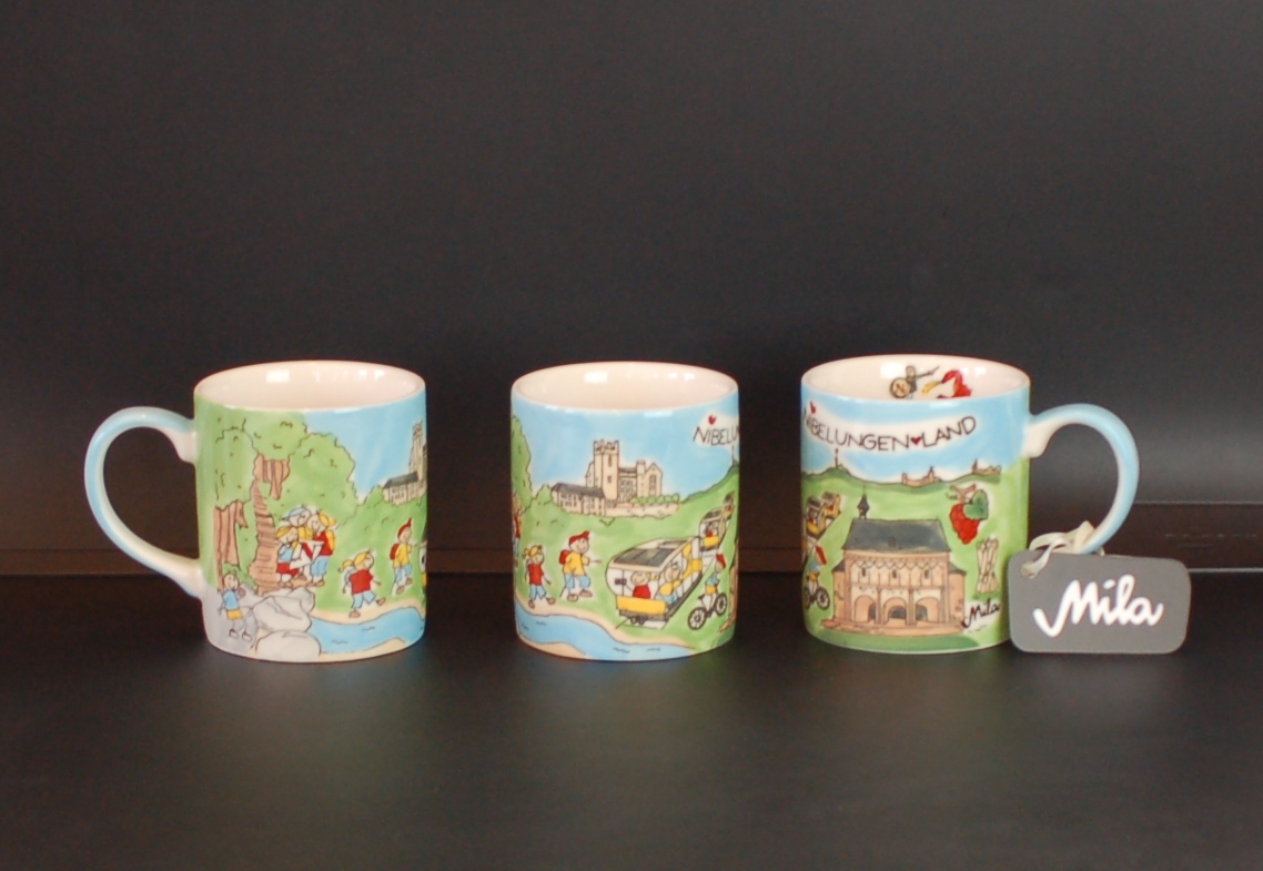 Drei Tassen mit bunten, handgemalten Szenen von Landschaften und kleinen Figuren, eine Tasse hat ein Schild mit der Aufschrift ‚Mila‘.