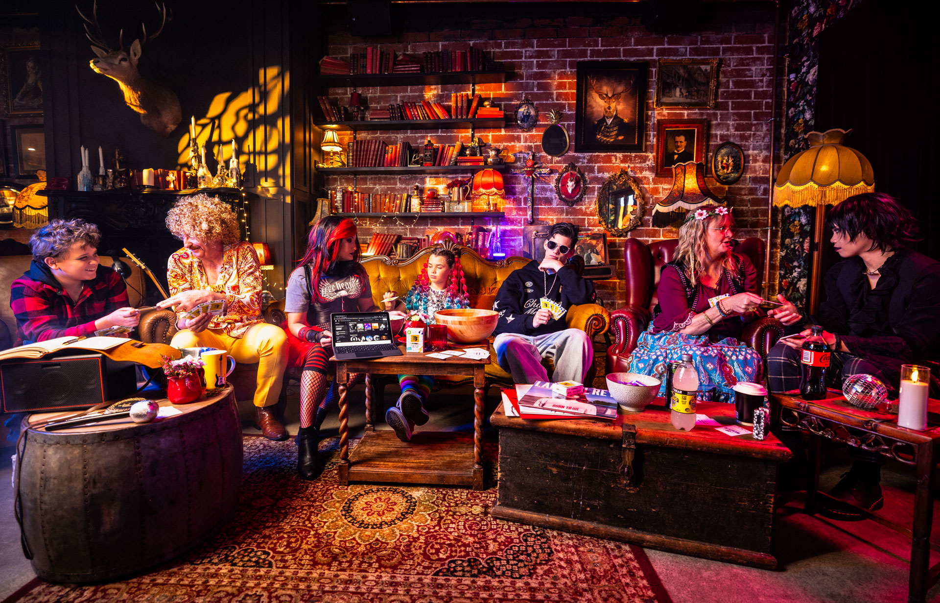 Group of seven people dressed in colourful and eclectic music genre-inspired clothes playing The Playlist Game.