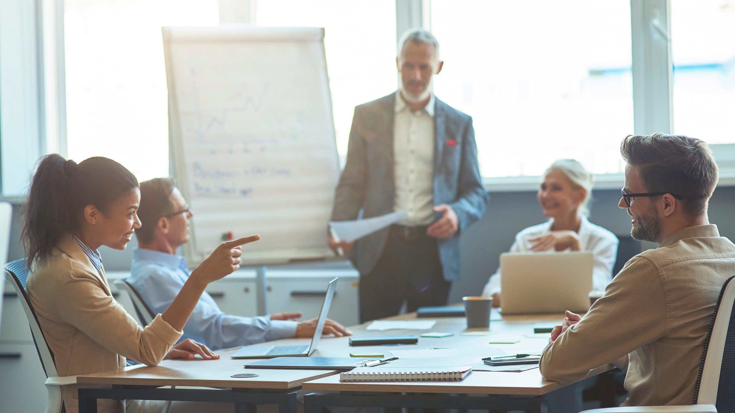 Vier Personen diskutieren engagiert bei einem Meeting im modernen Büro, eine Frau zeigt mit dem Finger.