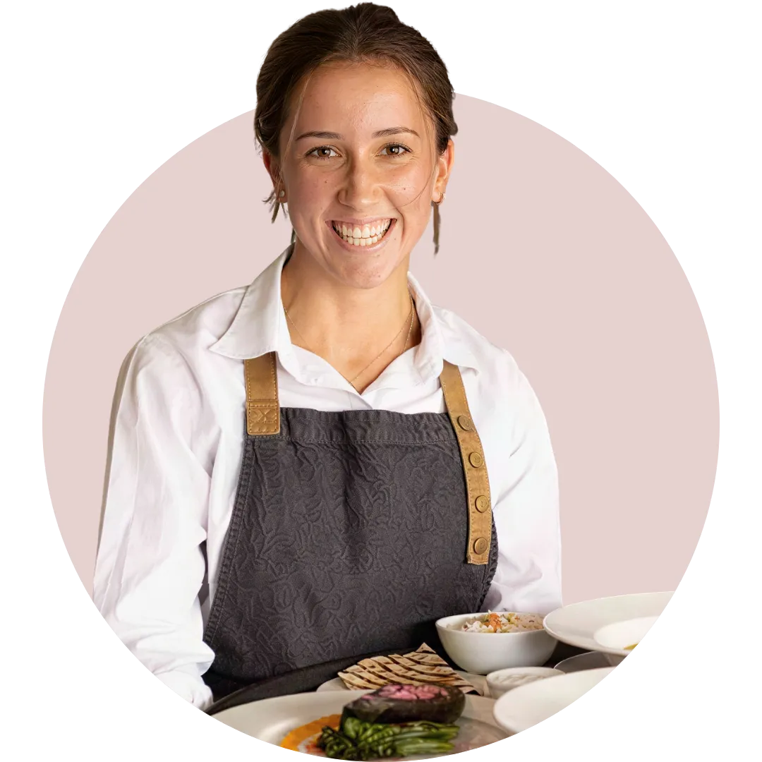 Smiling waitress in a modern restaurant setting, representing professional gastronomy staff for AV Group recruitment.