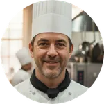 Professional chef in white uniform smiling in a modern hotel kitchen