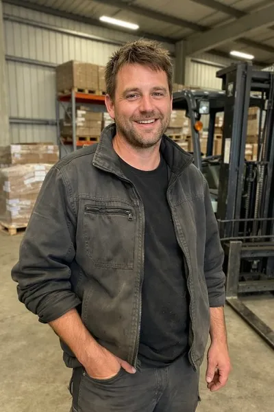 Experienced male forklift driver in a warehouse environment, ensuring safe goods transport.