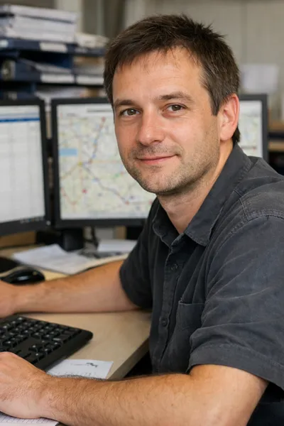 Focused male dispatcher coordinating transport and fleet logistics at a workstation.