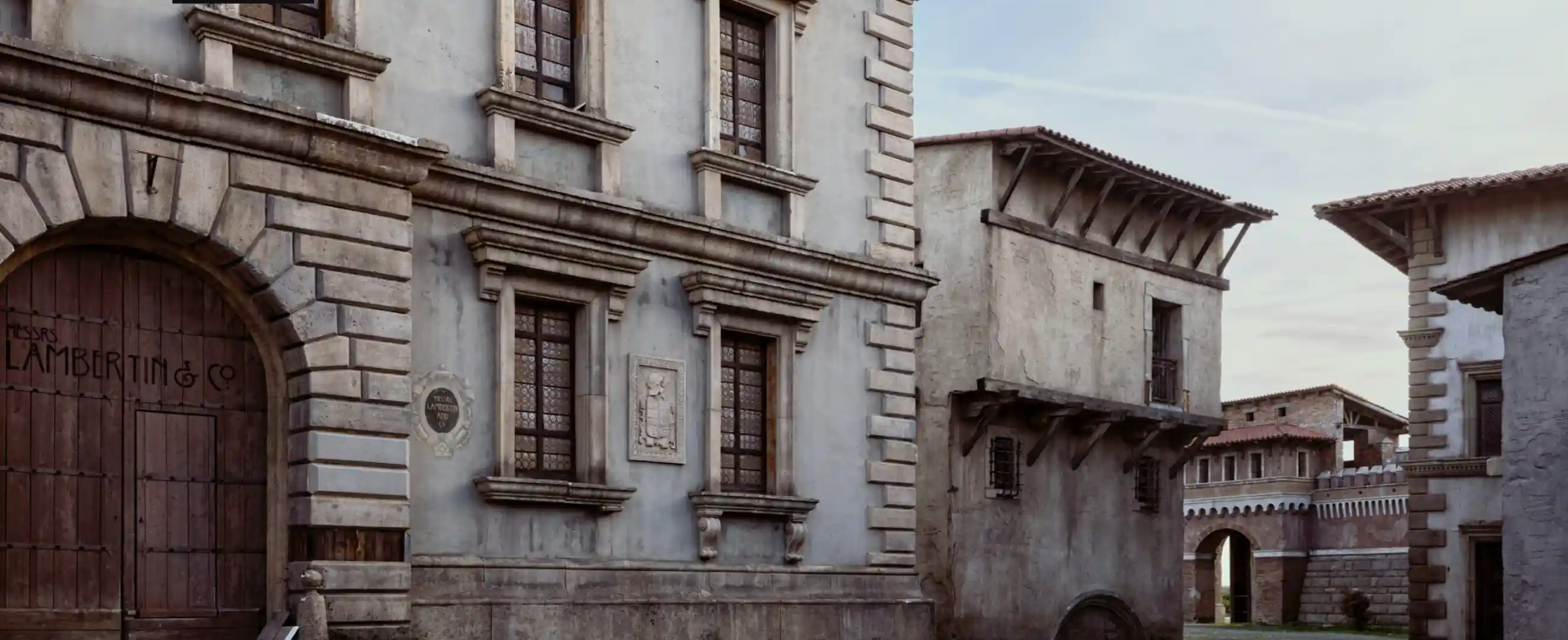 Historic stone buildings with arched wooden doors and detailed window frames under a clear sky.