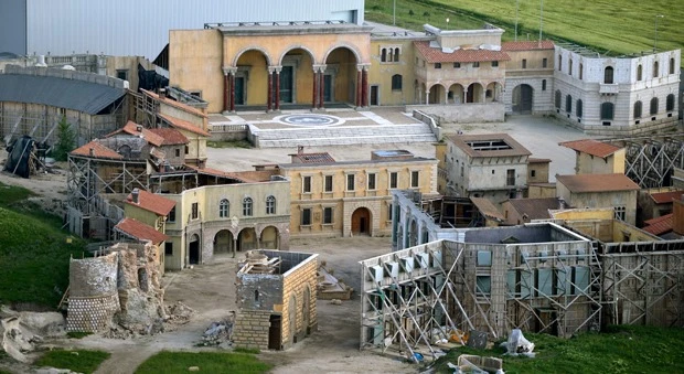 Detailed outdoor movie set featuring classical and Mediterranean-style buildings with scaffolding and a large courtyard.