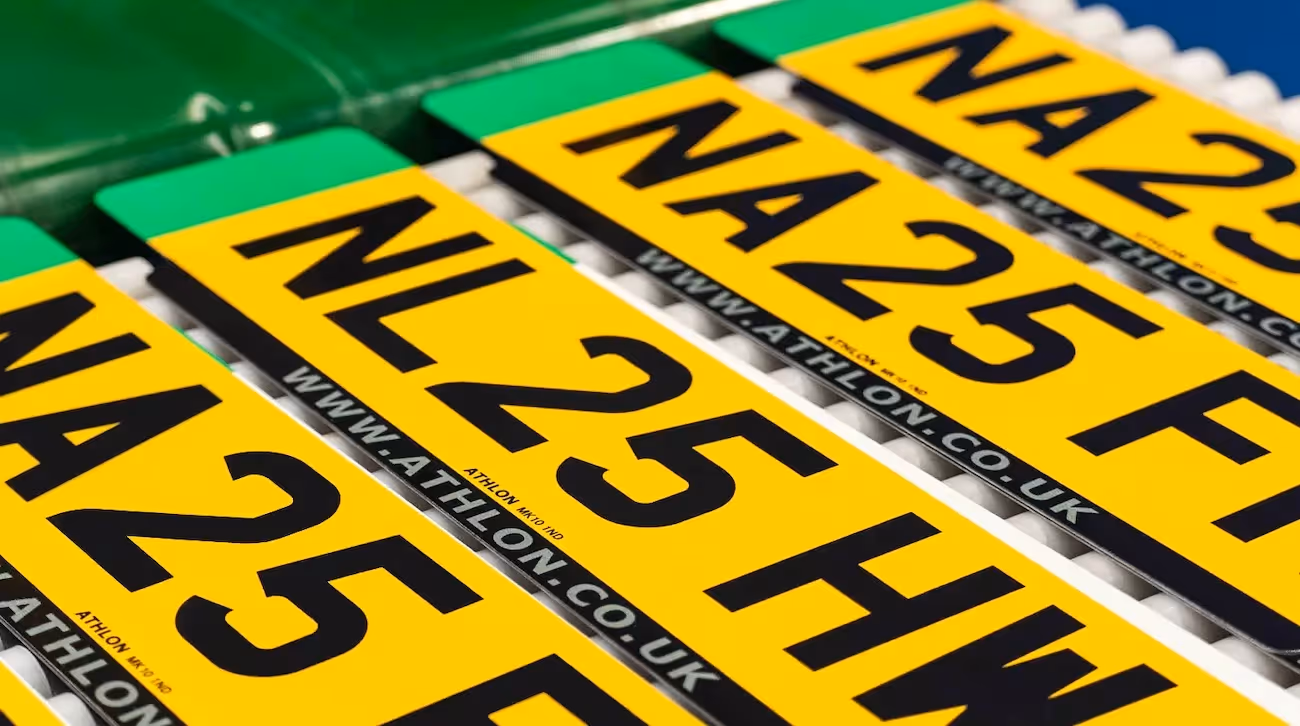 Four UK car number plates on a table. 