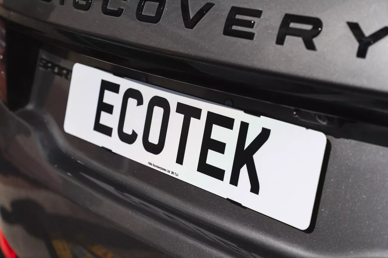 White aluminium front number plate displaying a private "ECOTEK" registration on a Land Rover Discovery