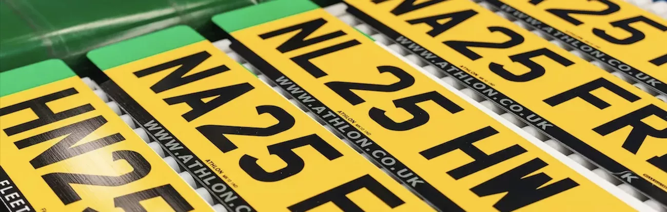 Close-up of yellow UK rear number plates printed with "25" registration codes and the athlon.co.uk website address.