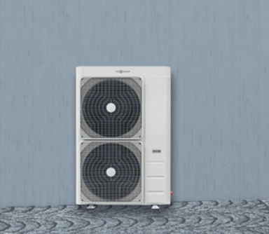 Unité de pompe à chaleur Viessmann avec deux ventilateurs, placée contre un mur gris sur un sol pavé.