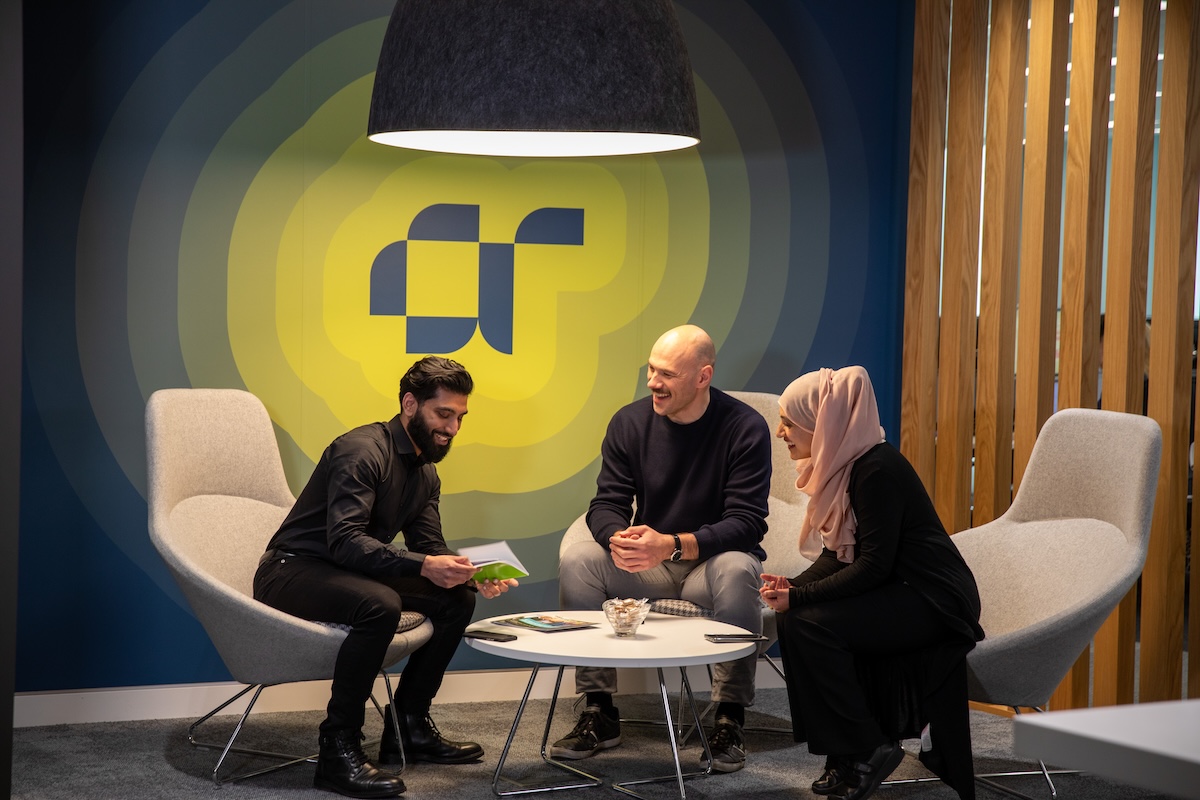 Three AtkinsRéalis employees sitting in a stylish office and having a friendly chat.