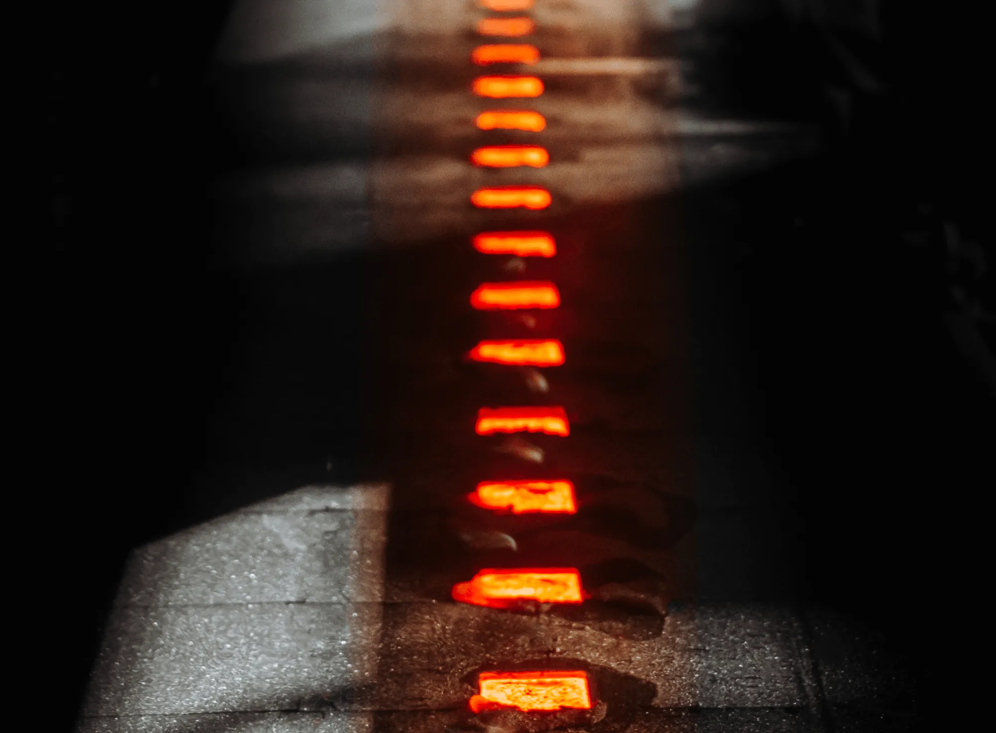 Close-up of glowing orange-red metal pieces on a dark surface with dim lighting.