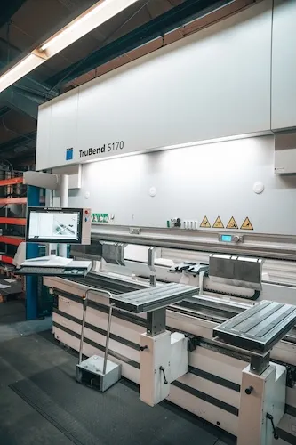 Industriemaschine TruBend 5170 mit Monitor und Metallbearbeitungstisch in einer Werkstatt.