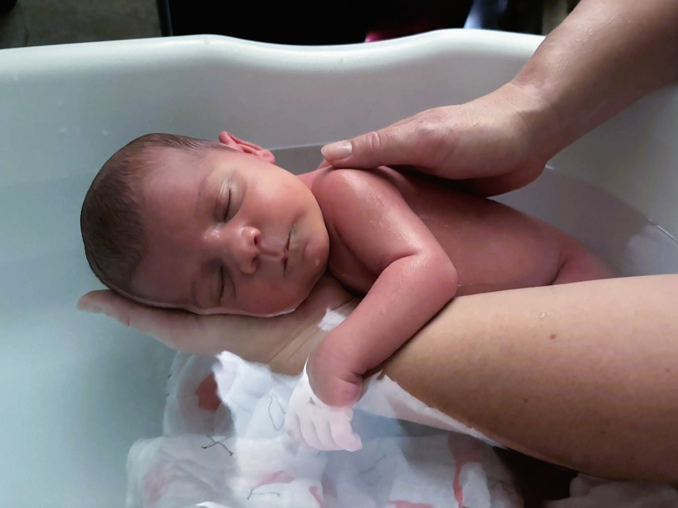 un bébé dormant dans l'eau dans les mains de Cyrielle