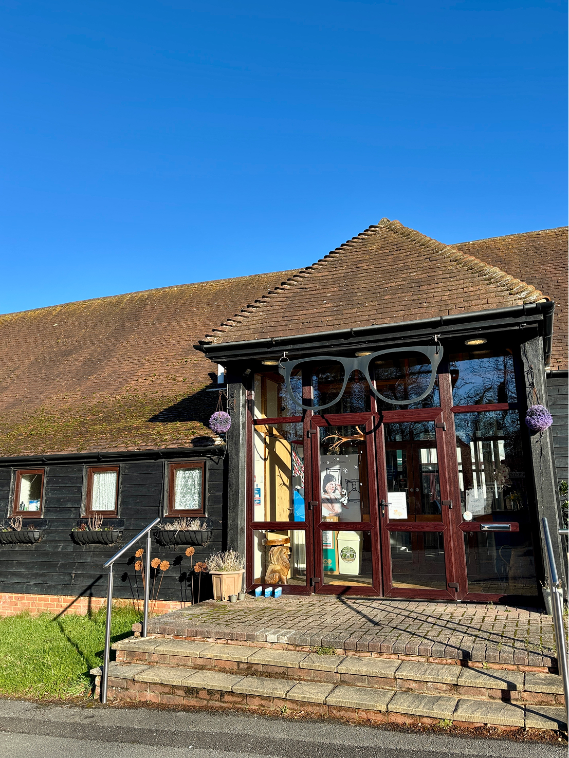 Rustic building entrance with large glasses sign, brick steps, blue sky