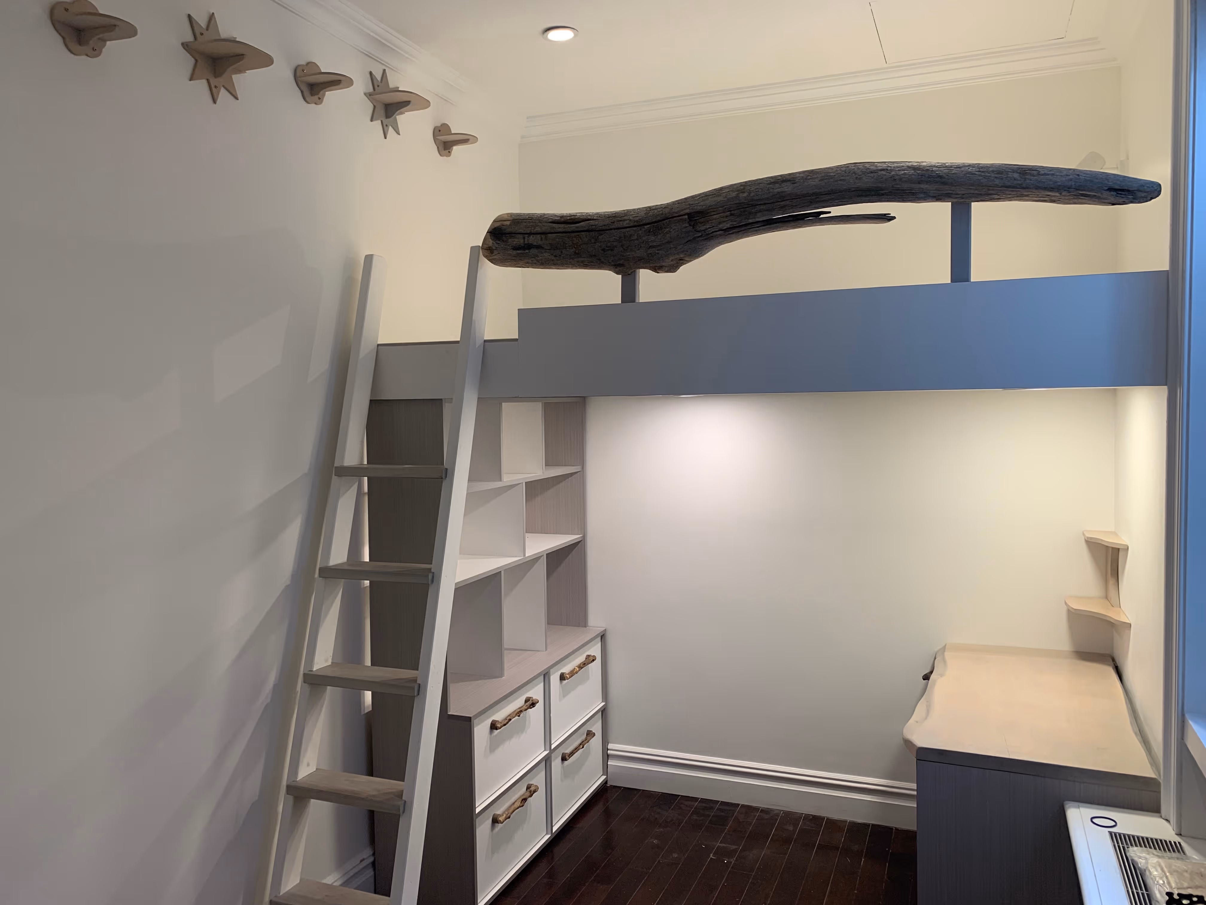 Minimalist loft bed with white ladder, built-in shelves and drawers, and a wooden desk with natural edge in a small room.