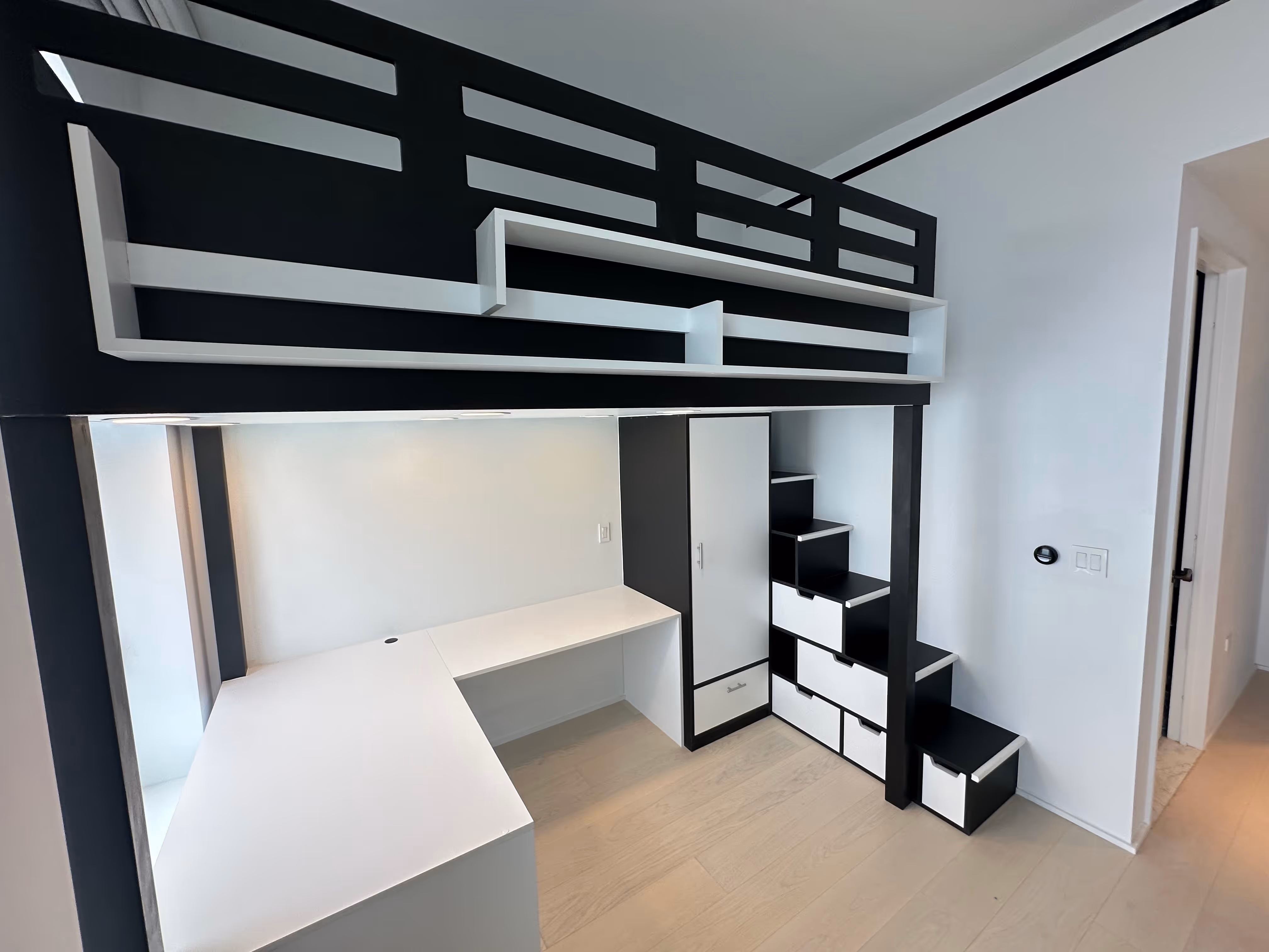 Modern black and white loft bed with built-in storage drawers and a spacious white L-shaped desk underneath.