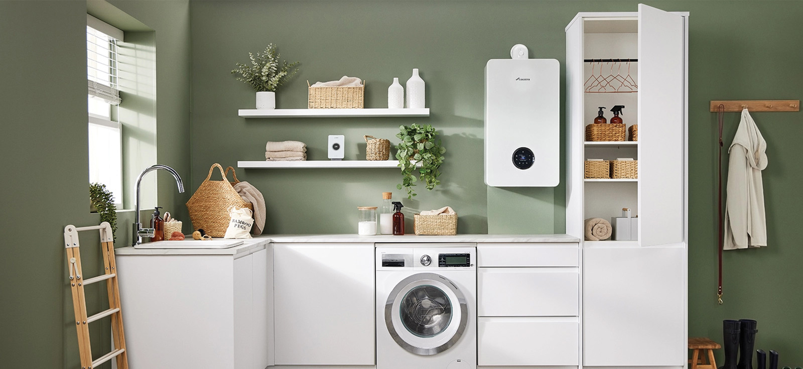 Modern laundry room with white cabinets, front-loading washing machine, green walls, shelving with baskets and plants, and a mounted water heater.
