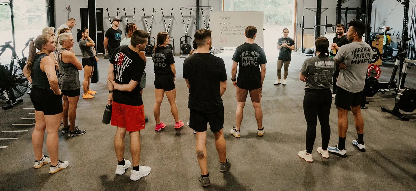 Group of people standing in a gym listening to a coach.