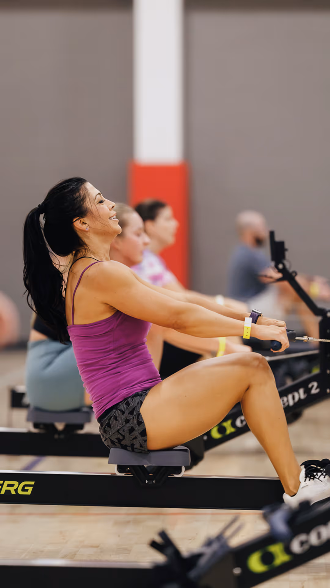 Smiling woman using a rowing machine in a gym class.
