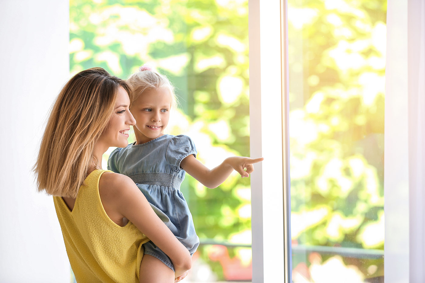 woman holding child looking out a window