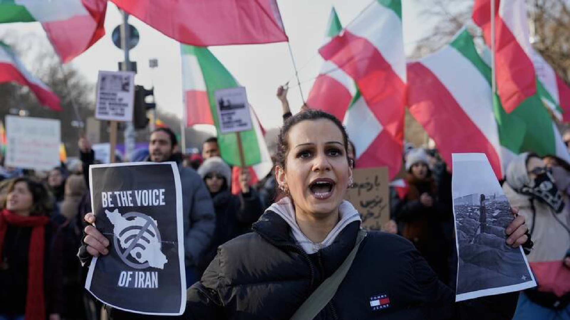 Woman holding posters at a rally protesting the Iranian regime 
