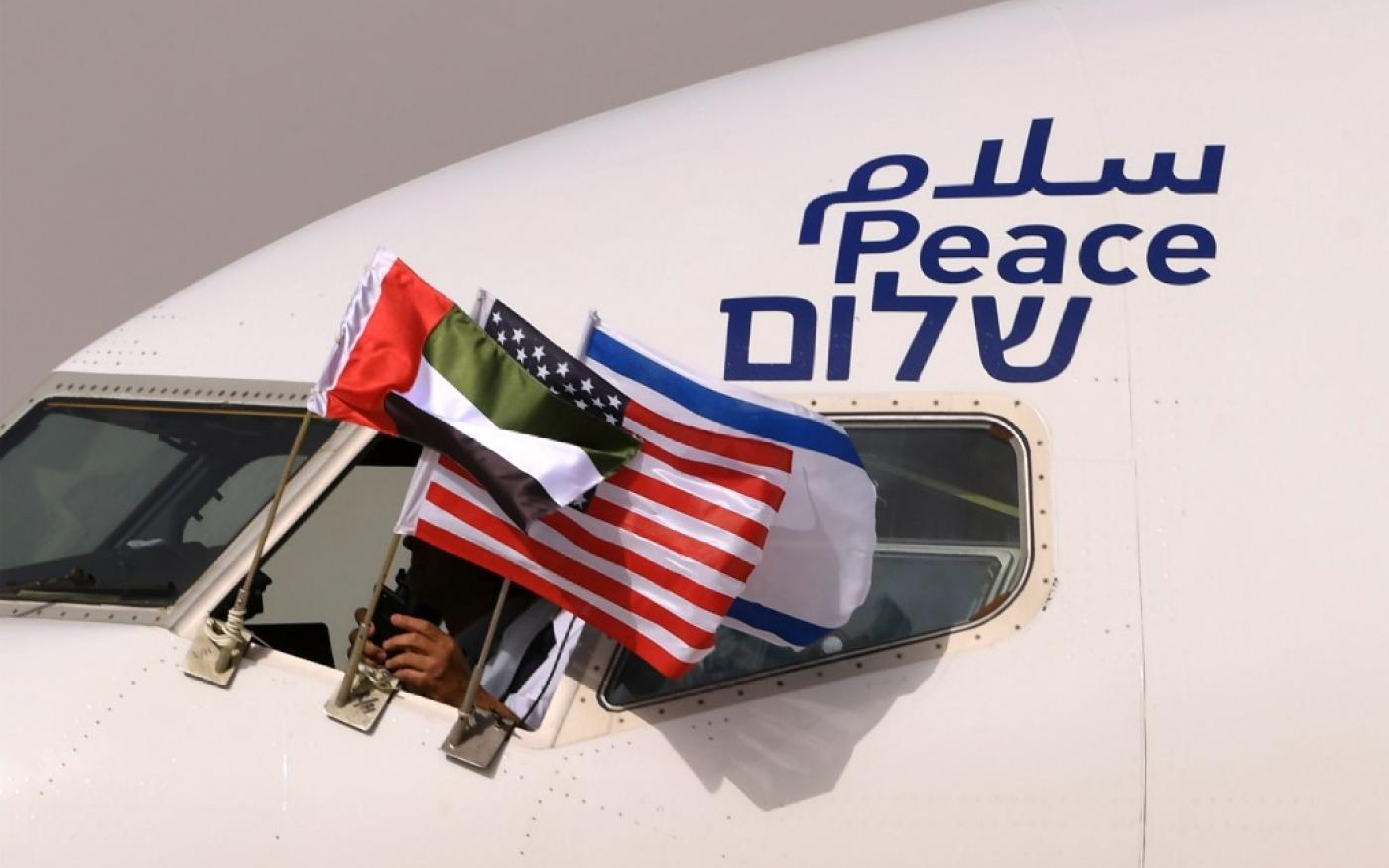 plane with israeli, uae and american flags waving through the cockpit window and "peace" written on the plane