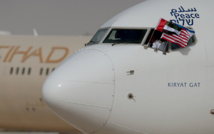 plane with israeli, uae and american flags waving through the cockpit window and "peace" written on the plane