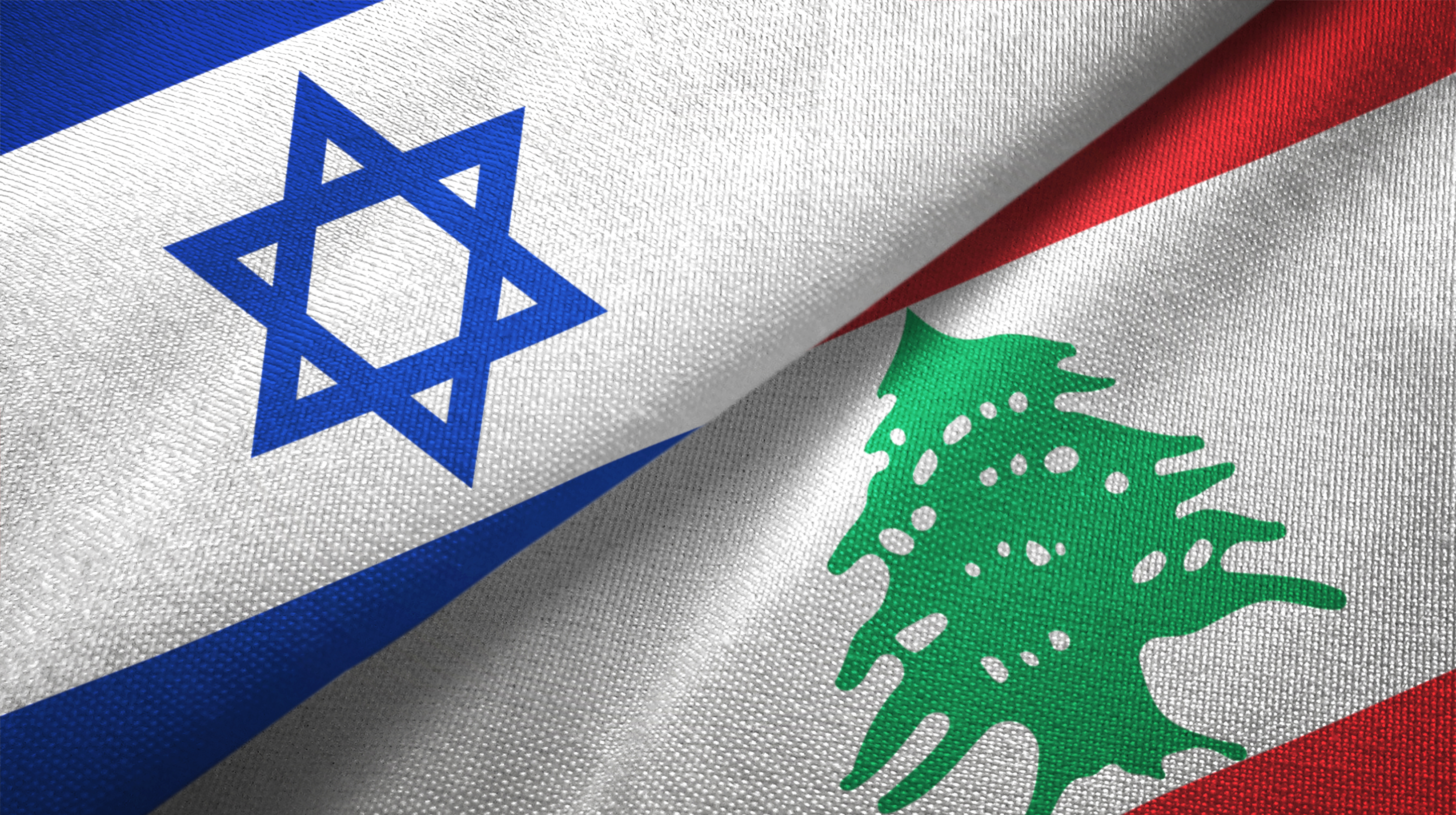 Close-up of folded Israeli flag with Star of David and Lebanese flag with cedar tree.