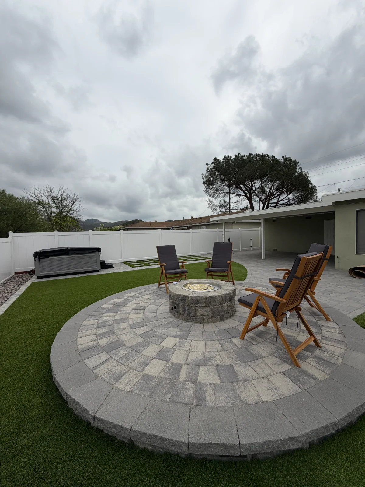 Front yard of a house with bright green artificial grass and rectangular stepping stones embedded in the grass leading to the entrance.