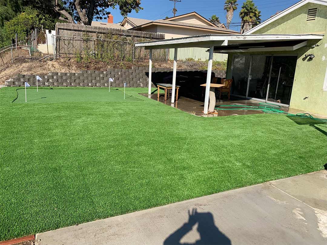 Front yard of a house with artificial grass and stepping stone pathway leading to the entrance.