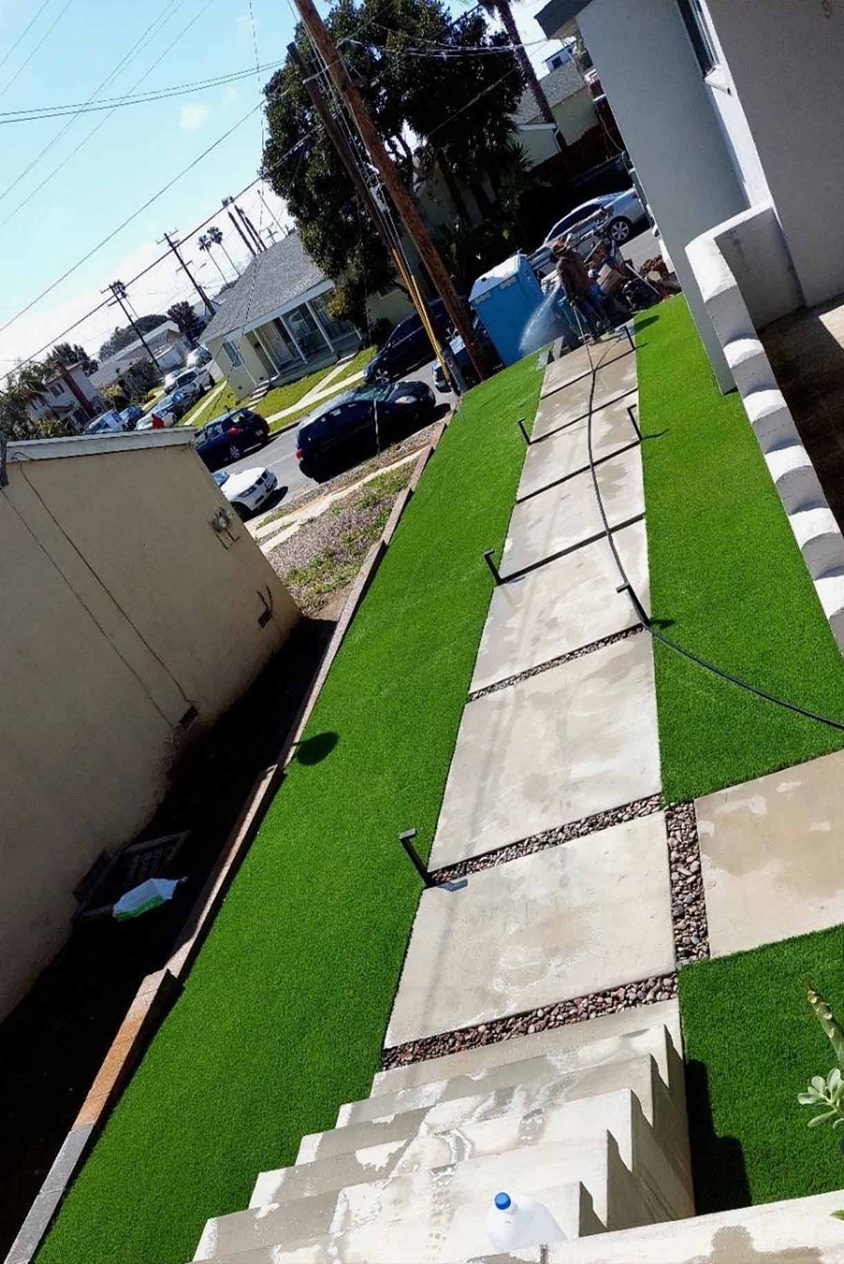 Front yard of a house with artificial grass and stepping stone pathway leading to the entrance.