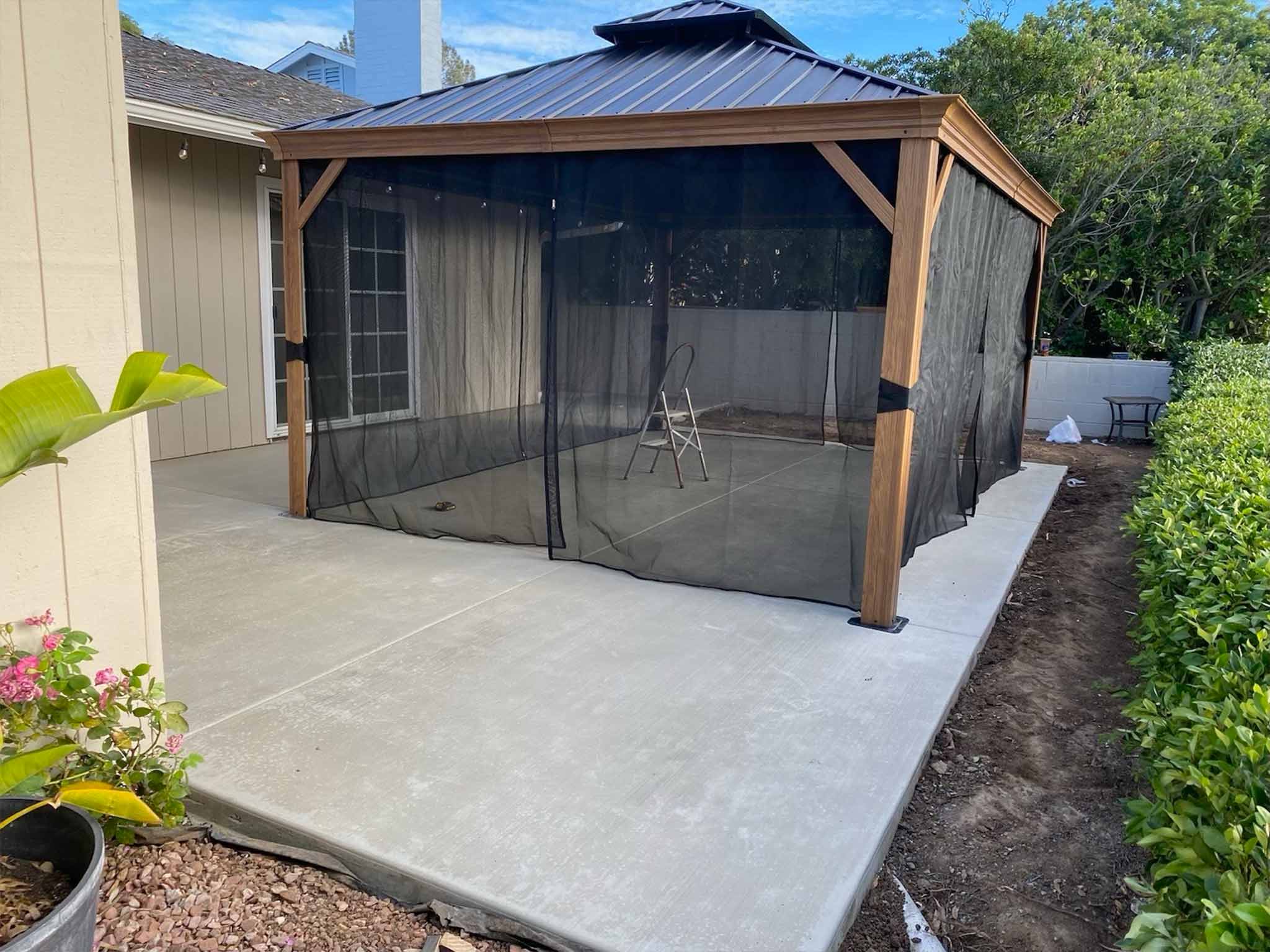 Well-manicured front yard with bright green grass, a large leafy plant cluster, a small palm tree, and a pathway leading to a blue house entrance.