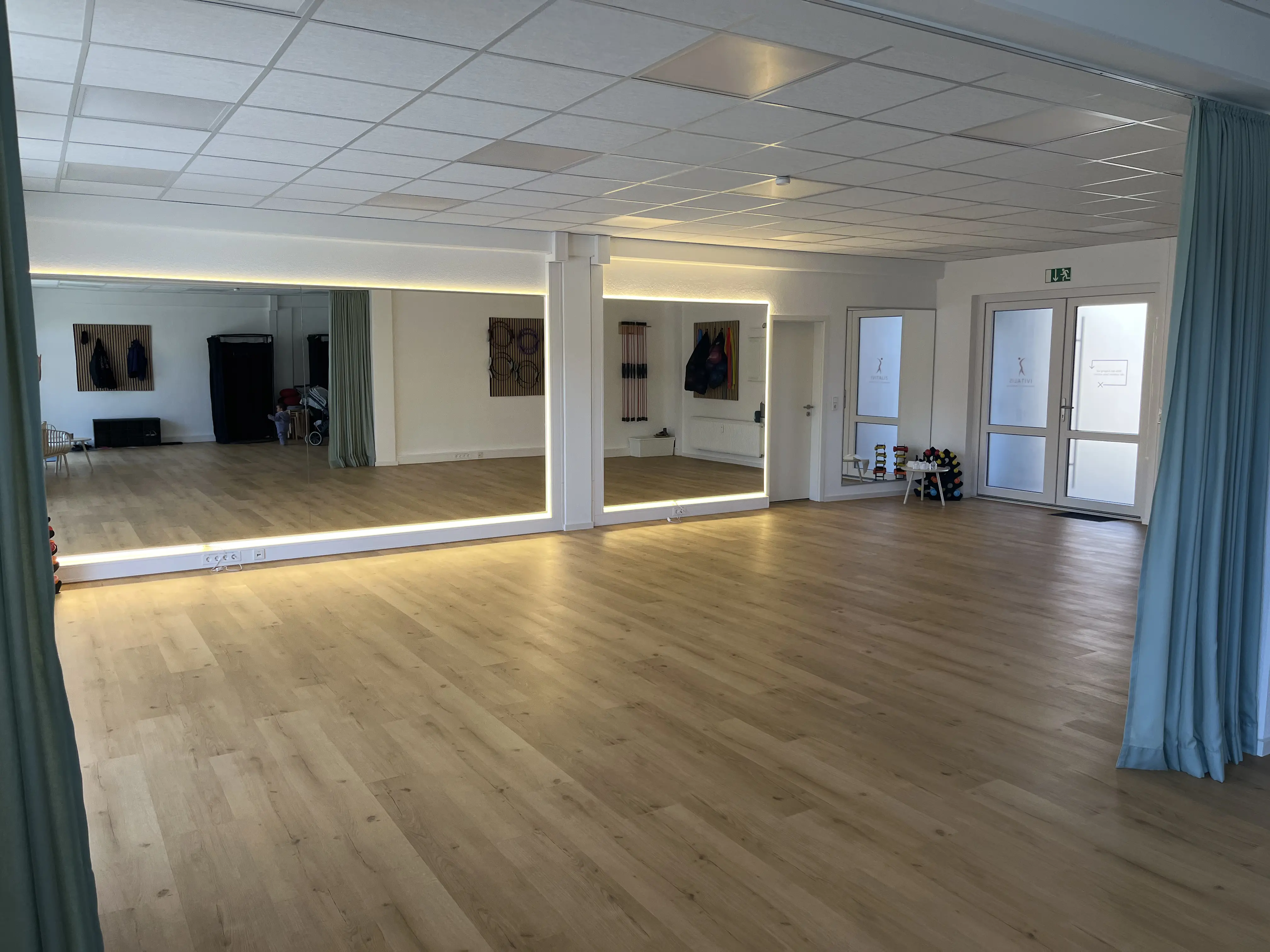 Empfangsraum im IVITALIS Studio Braunschweig-Querum mit geöffnetem Vorhang und Blick in den Kursbereich
