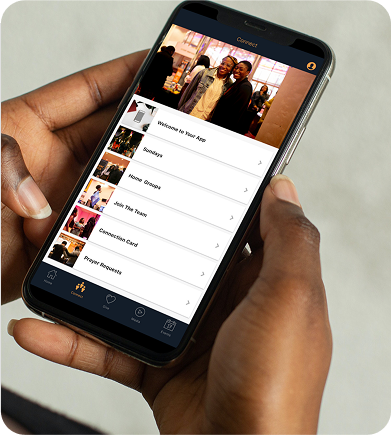 Hand holding a smartphone displaying a church app interface with sections like Sunday, Home Groups, Join The Team, Connection Card, and Prayer Requests.