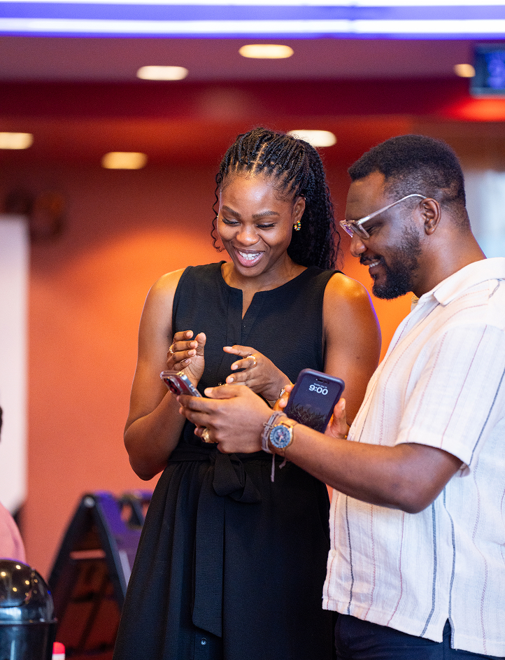 Smiling woman and man looking at smartphones together indoors.