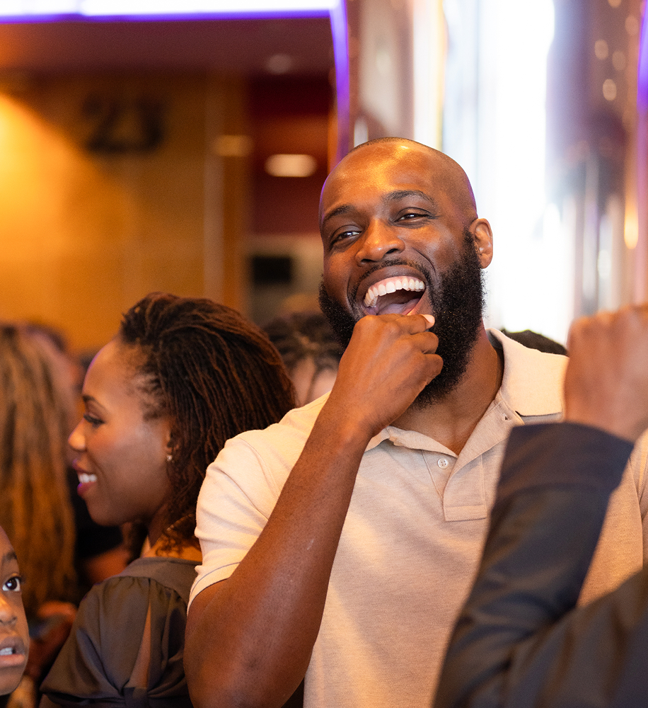 Smiling man with a beard laughing and enjoying himself in a social gathering.