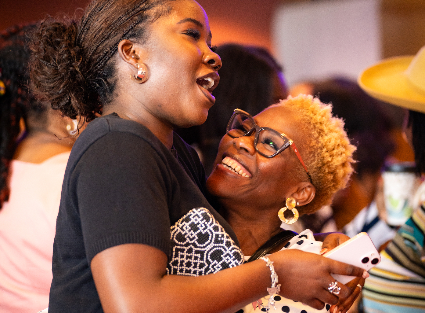 Two women warmly embracing and smiling at a social event.